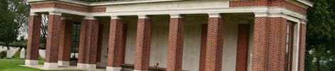 A classic brick building with columns, set in green surroundings