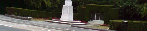 A white monument in a green park with hedges