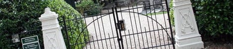Sierlijk zwart ijzeren toegangshek met witte stenen pijlers
